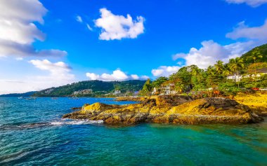 İnanılmaz kayalık Kalim Sahili tropikal manzara manzarası mavi gökyüzü turkuvaz su dalgaları palmiye ağaçları ve kayalar Patong Sahili Kathu Phuket Adası Güney Tayland.