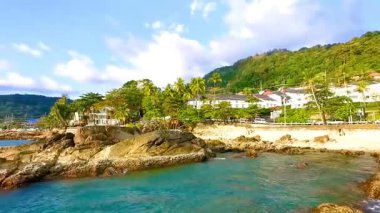 İnanılmaz kayalık Kalim Sahili tropikal manzara manzarası mavi gökyüzü turkuvaz su dalgaları palmiye ağaçları ve kayalar Patong Sahili Kathu Phuket Adası Güney Tayland.