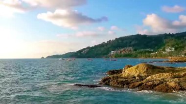 İnanılmaz kayalık Kalim Sahili tropikal manzara manzarası mavi gökyüzü turkuvaz su dalgaları palmiye ağaçları ve kayalar Patong Sahili Kathu Phuket Adası Güney Tayland.