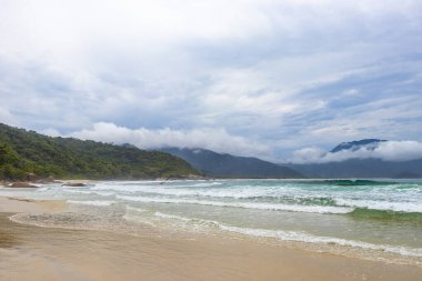 Aventureiro Sahili tropikal manzara manzarası turkuaz mavi su dalgaları palmiye ağaçları ve bulutlu mavi gökyüzü Ilha Grande Büyük Adası Angra dos Reis Rio de Janeiro Brezilya.