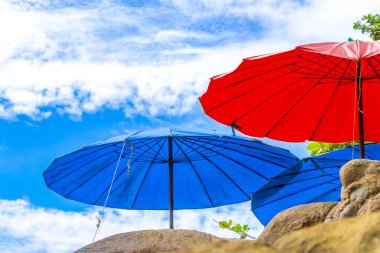 Patong Sahili turizm hangarı güneş şemsiyeleriyle güneşli güneşli güneşli su dalgaları mavi gökyüzü kayaları ve tropikal palmiye ağaçları Patong Sahili 'nde Kathu Phuket Adası Güney Tayland' da.