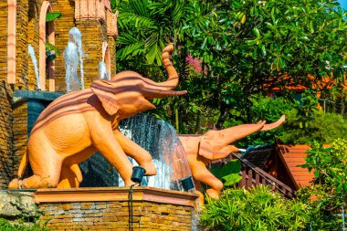 Kathu Bölgesi Phuket Adası Eyaleti Güney Tayland 29. Kasım 2025 Novotel tatil köyünde tropikal bitkiler, palmiye ağaçları fil heykelleri, çeşmeler ve Patong Sahili girişi..