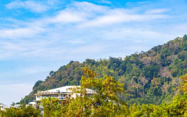 Tropik dağ tepeleri orman yağmur ormanları ağaçlarının tepeleri palmiye ağaçları bulut ve mavi gökyüzü manzarası Patong Sahili Kathu Bölgesi Phuket Adası Güney Tayland.