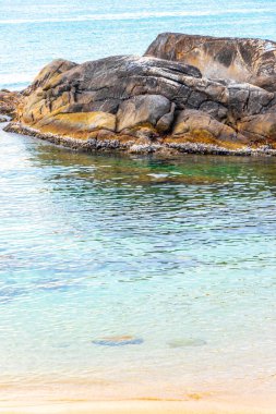 Rocky Kalim Sahili tropikal sahil kıyısı turkuvaz mavisi berrak su dalgaları kum kayaları kaya ve midye kabuklu kayalar Patong Sahili Kathu Phuket Adası Güney Tayland.