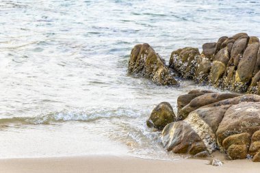Rocky Kalim Sahili tropikal sahil kıyısı turkuvaz mavisi berrak su dalgaları kum kayaları kaya ve midye kabuklu kayalar Patong Sahili Kathu Phuket Adası Güney Tayland.