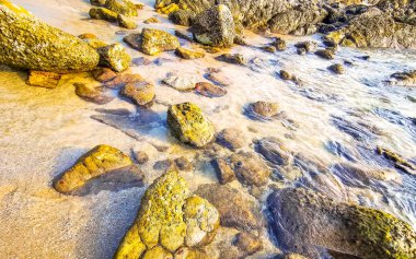 Rocky Kalim Sahili tropikal sahil kıyısı turkuvaz mavisi berrak su dalgaları kum kayaları kaya ve midye kabuklu kayalar Patong Sahili Kathu Phuket Adası Güney Tayland.