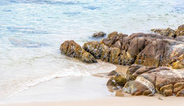 Rocky Kalim Sahili tropikal sahil kıyısı turkuvaz mavisi berrak su dalgaları kum kayaları ve kayalar Patong Sahili Kathu Bölgesi Phuket Adası Güney Tayland Bölgesi.