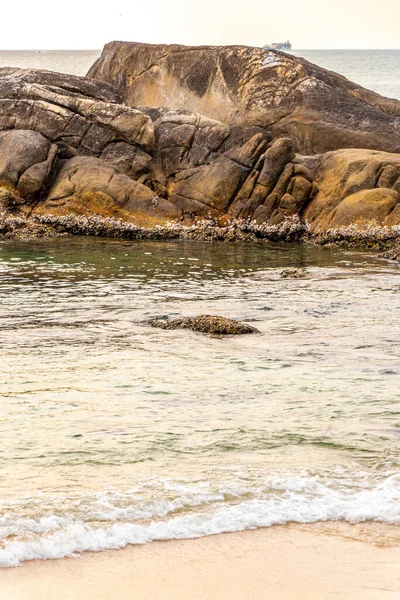 Rocky Kalim Sahili tropikal sahil kıyısı turkuvaz mavisi berrak su dalgaları kum kayaları kaya ve midye kabuklu kayalar Patong Sahili Kathu Phuket Adası Güney Tayland.
