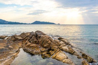 Rocky Kalim Sahili tropikal sahil kıyısı turkuvaz mavisi berrak su dalgaları kum kayaları ve kayalar Patong Sahili Kathu Bölgesi Phuket Adası Güney Tayland Bölgesi.