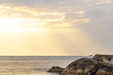 Rocky Kalim Sahili tropikal deniz kıyısı gün batımı güneş doğumu turkuvaz mavisi yeşil su dalgaları kum kayaları ve kayalar Patong Sahili Kathu Phuket Adası Tayland.