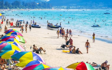 Kathu Bölgesi Phuket Adası, Tayland 06. Şubat 2026 Patong Sahil Koyu turistlerle su dalgaları güneş şemsiyeleri tropik bitkiler ve palmiye ağaçları Phuket Tayland 'da.