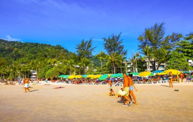 Kathu Bölgesi Phuket Adası, Tayland 05. Şubat 2026 Patong Sahil Koyu turistlerle su dalgaları güneş şemsiyeleri tropik bitkiler ve palmiye ağaçları Phuket Tayland 'da.