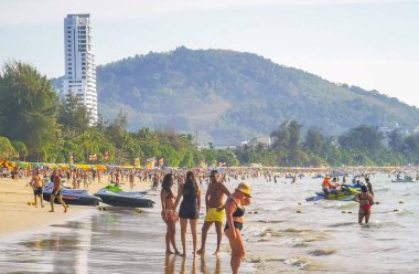Kathu Bölgesi Phuket Adası, Tayland 05. Şubat 2026 Patong Sahil Koyu turistlerle su dalgaları güneş şemsiyeleri tropik bitkiler ve palmiye ağaçları Phuket Tayland 'da.