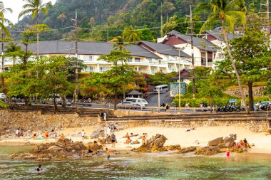 Kathu Bölgesi, Phuket Adası, Tayland 11. Şubat 2026 Kalim Sahili tropikal manzara manzarası turistlerle su dalgaları palmiye ağaçları Patong Sahili Tayland 'da kayalar.