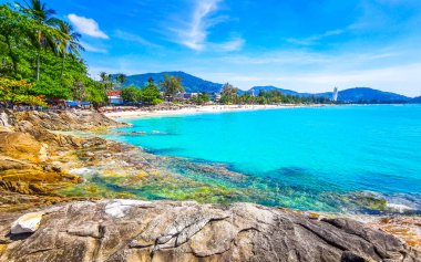 İnanılmaz kayalık Patong Kamala Sahili tropikal manzara manzarası mavi gökyüzü turkuvaz deniz suyu dalgaları palmiye ağaçları ve kayalar Patong Sahili Kathu Phuket Adası Güney Tayland.
