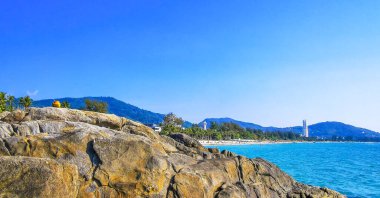 Patong Kamala Sahili tropikal manzara manzarası. Mavi gökyüzü turkuvaz deniz suyu dalgaları palmiye ağaçları. Patong Sahili 'ndeki kayalar..