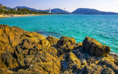 Patong Kamala Sahili tropikal manzara manzarası. Mavi gökyüzü turkuvaz deniz suyu dalgaları palmiye ağaçları. Patong Sahili 'ndeki kayalar..