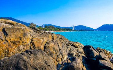 Patong Kamala Sahili tropikal manzara manzarası. Mavi gökyüzü turkuvaz deniz suyu dalgaları palmiye ağaçları. Patong Sahili 'ndeki kayalar..