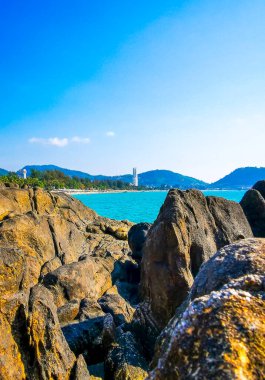 Patong Kamala Sahili tropikal manzara manzarası. Mavi gökyüzü turkuvaz deniz suyu dalgaları palmiye ağaçları. Patong Sahili 'ndeki kayalar..