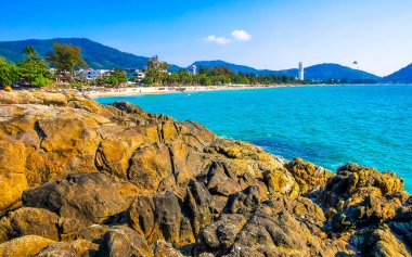 Patong Kamala Sahili tropikal manzara manzarası mavi gökyüzü turkuvaz deniz suyu dalgaları palmiye ağaçları ve kayalar Patong Sahili 'nde Kathu Phuket Adası Güney Tayland.