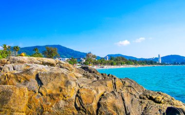 Patong Kamala Sahili tropikal manzara manzarası mavi gökyüzü turkuvaz deniz suyu dalgaları palmiye ağaçları ve kayalar Patong Sahili 'nde Kathu Phuket Adası Güney Tayland.