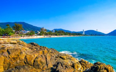 Patong Kamala Sahili tropikal manzara manzarası mavi gökyüzü turkuvaz deniz suyu dalgaları palmiye ağaçları ve kayalar Patong Sahili 'nde Kathu Phuket Adası Güney Tayland.