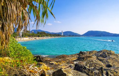 Patong Kamala Sahili tropikal manzara manzarası mavi gökyüzü turkuvaz deniz suyu dalgaları palmiye ağaçları ve kayalar Patong Sahili 'nde Kathu Phuket Adası Güney Tayland.