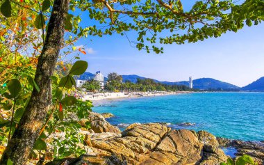Patong Kamala Sahili tropikal manzara manzarası mavi gökyüzü turkuvaz deniz suyu dalgaları palmiye ağaçları ve kayalar Patong Sahili 'nde Kathu Phuket Adası Güney Tayland.