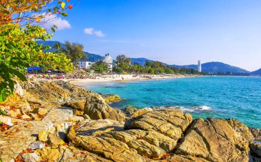 Patong Kamala Sahili tropikal manzara manzarası mavi gökyüzü turkuvaz deniz suyu dalgaları palmiye ağaçları ve kayalar Patong Sahili 'nde Kathu Phuket Adası Güney Tayland.