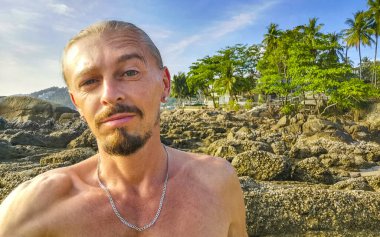 Güneydoğu Asya 'daki Güney Tayland' da Patong Sahili 'nde turkuvaz mavisi su kayaları ve beyaz kumla tropikal Patong Sahili' ndeki yakışıklı erkek turist..