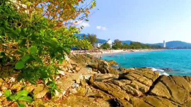 Kathu Bölgesi Phuket Adası, Tayland 25. Şubat 2026 Patong Kamala Sahili Turistlerle su dalgaları güneş şemsiyeleri tropik palmiye ağaçları ve Tayland 'da kayalık merdivenler.