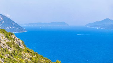 Sahil kıyısı turkuvaz mavi su dalgaları ada adaları dağ tepeleri kayalık tepeler uçurumlar ve Dubrovnik Neretva İlçesi Dalmaçya Bölgesi 'ndeki mavi gökyüzü manzarası Hırvatistan.