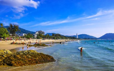 Kathu Bölgesi Phuket Adası, Tayland 04. Mart 2026 Patong Kamala Sahil Koyu 'nda turistler su dalgaları güneş şemsiyeleri tropik bitkiler kayalar ve Tayland palmiyeleri.
