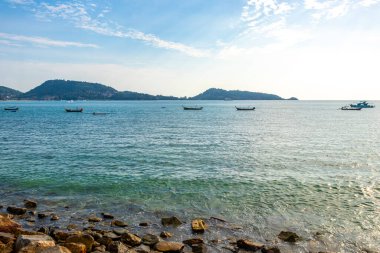 Tropikal Kalim Sahili kayalık sahil kıyısı turkuvaz mavisi açık deniz dalgaları kum kayaları ve kayalar Patong Sahili Kathu Bölgesi Phuket Adası Güney Tayland Bölgesi.