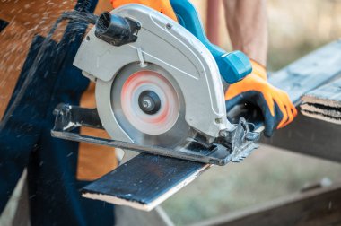 Marangoz siyah boyalı bir tahtayı testereyle kesiyor..