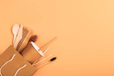 Kağıt ve ahşap tek kullanımlık sofra takımı ve hijyen malzemeleri bej arka planda bir kese kağıdında. Çevre dostu araçlar kavramı