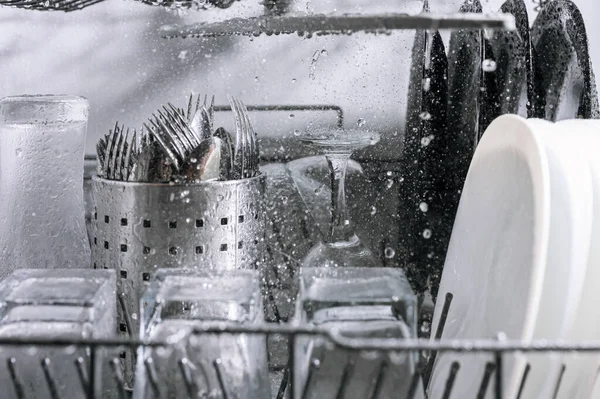 Dishes are washed in the dishwasher a lot of water splashes, close-up view from the inside selective focus