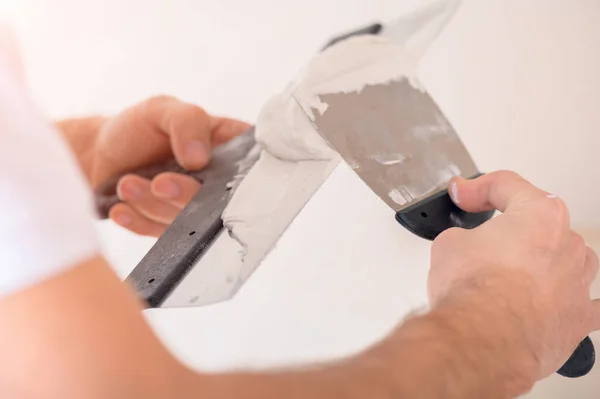 Elinde iki spatula olan bir adam macun kullanır, çok yakından seçici bir odak.