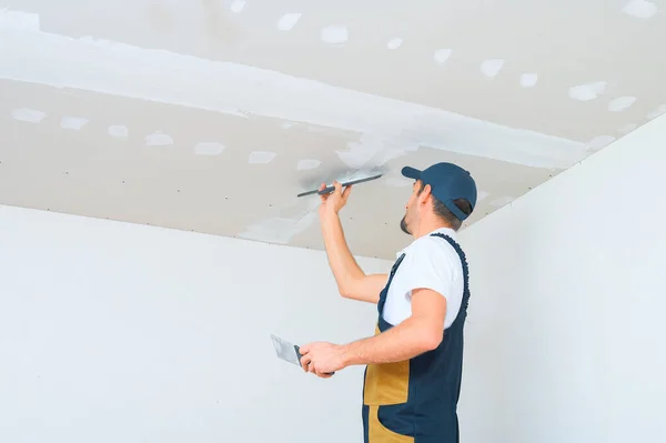 Ein Uniformierter Arbeiter Trägt Spachtel Auf Die Trockenbaudecke Auf Kitt — Stockfoto