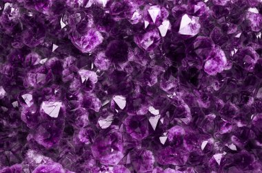 Mor gölgelerle parıldayan bir mineral değerli ya da yarı değerli ametist taşının dokusu yakın plandadır..