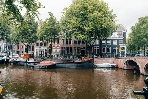 Bisikletler ve antik mimari ile süslenmiş Amsterdam kanalı manzarası..
