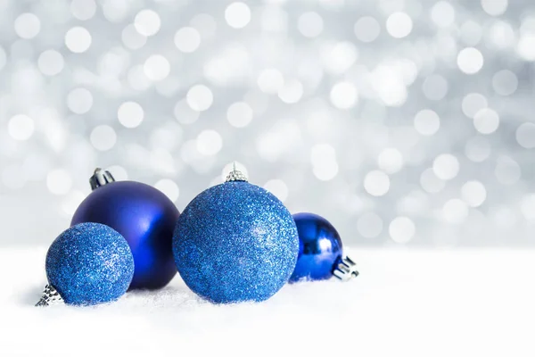 Kar arka planında Noel mavisi süslemeleri.