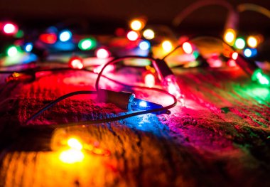 Noel, koyu ahşap arka planda bulanık renkli ışıklar. Dekoratif bokeh ışıkları, çelenk.