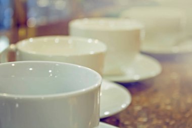 Masada ve kafenin arkasında bir sürü beyaz kahve fincanı var..