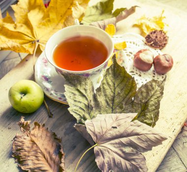 Bir fincan çay, sonbahar yaprakları ve elmalar, üst manzara..