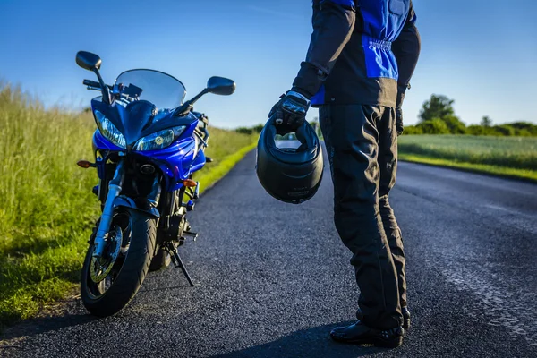 Motocicleta e motorista em estrada solitária — Fotografia de Stock
