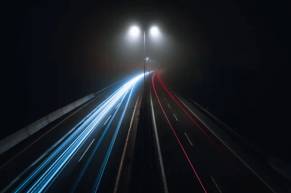 Poziome Zdjęcie Samochodów Lekkich Szlaków Zakrzywionej Autostradzie Nocy Lampami Ulicznymi — Zdjęcie stockowe