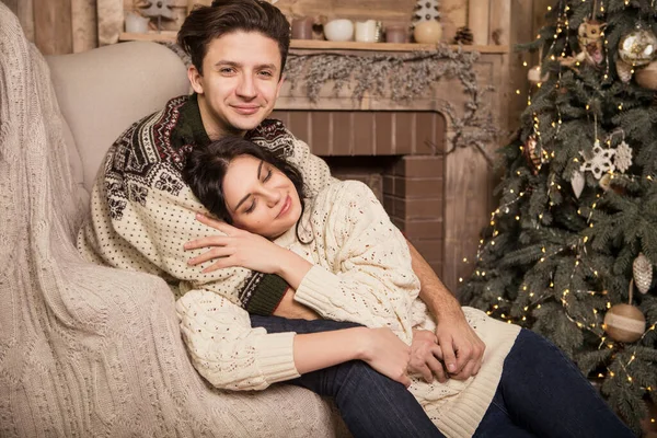 在圣诞节前夕 穿着舒适温暖的毛衣 面带微笑 彼此寻欢作乐的美丽的黑发情爱的夫妇在小木屋里共度佳节 昏暗的夜光 柔和的图像 — 图库照片