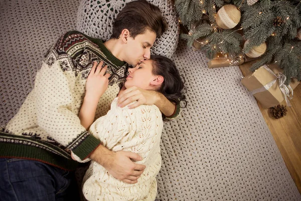在圣诞节前夕 穿着舒适温暖的毛衣 面带微笑 彼此寻欢作乐的美丽的黑发情爱的夫妇在小木屋里共度佳节 昏暗的夜光 柔和的图像 — 图库照片