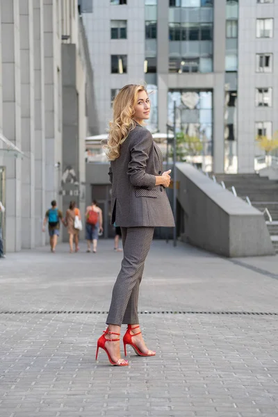 美丽的金发女人穿着灰色经典的智能休闲装站在高科技商业大楼附近 案文的篇幅 — 图库照片